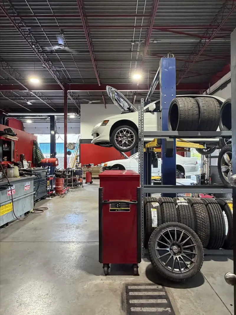 Atelier du garage à St-Léonard : rangée de pneus et auto sur le pont élévateur